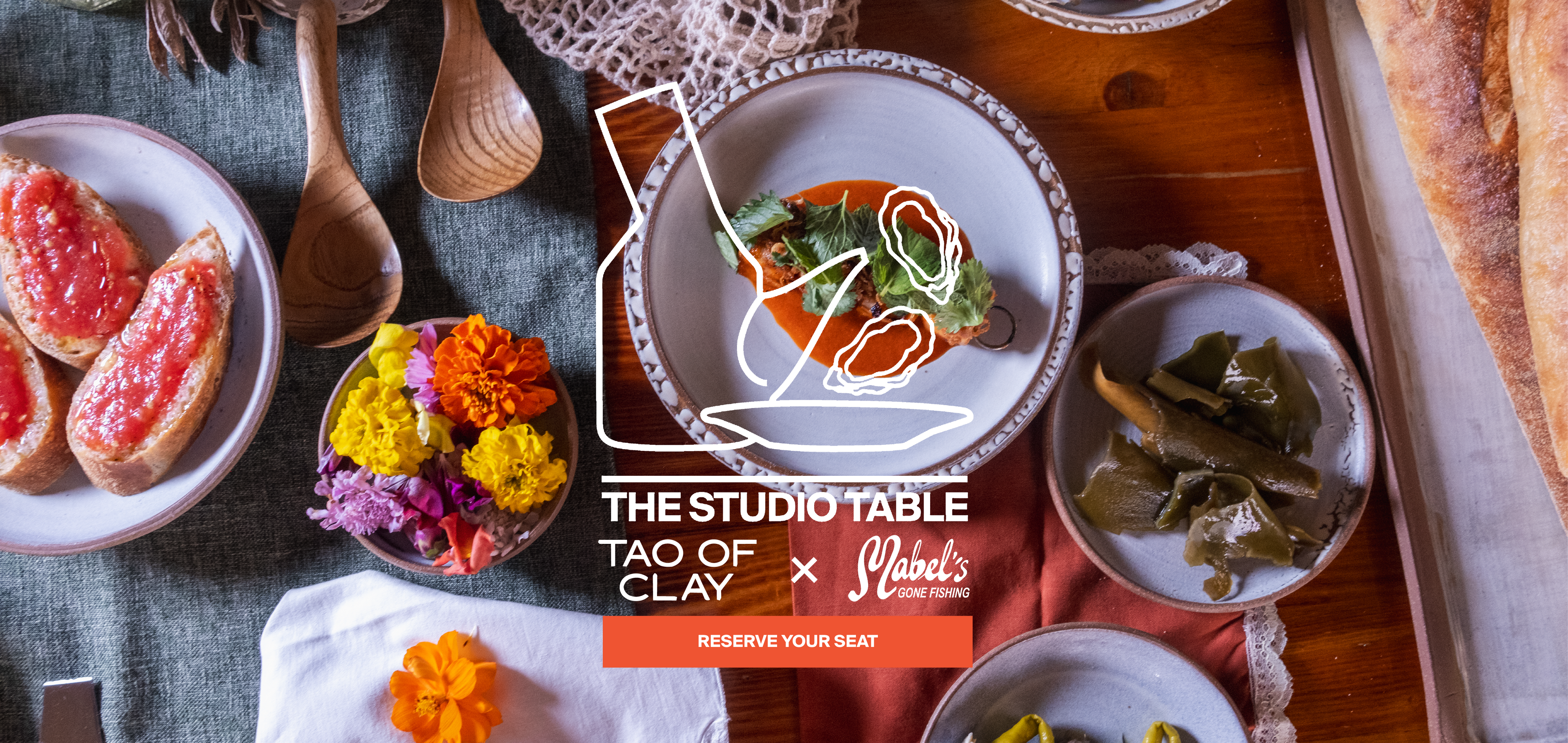 Overhead styled dining scene with plates of food on a wooden table, including bread, oysters, olives, pickles, and a central bowl. A large overlaid logo and text read 'THE STUDIO TABLE TAO OF CLAY x Mabel's Gone Fishing' with 'RESERVE YOUR SEAT'.