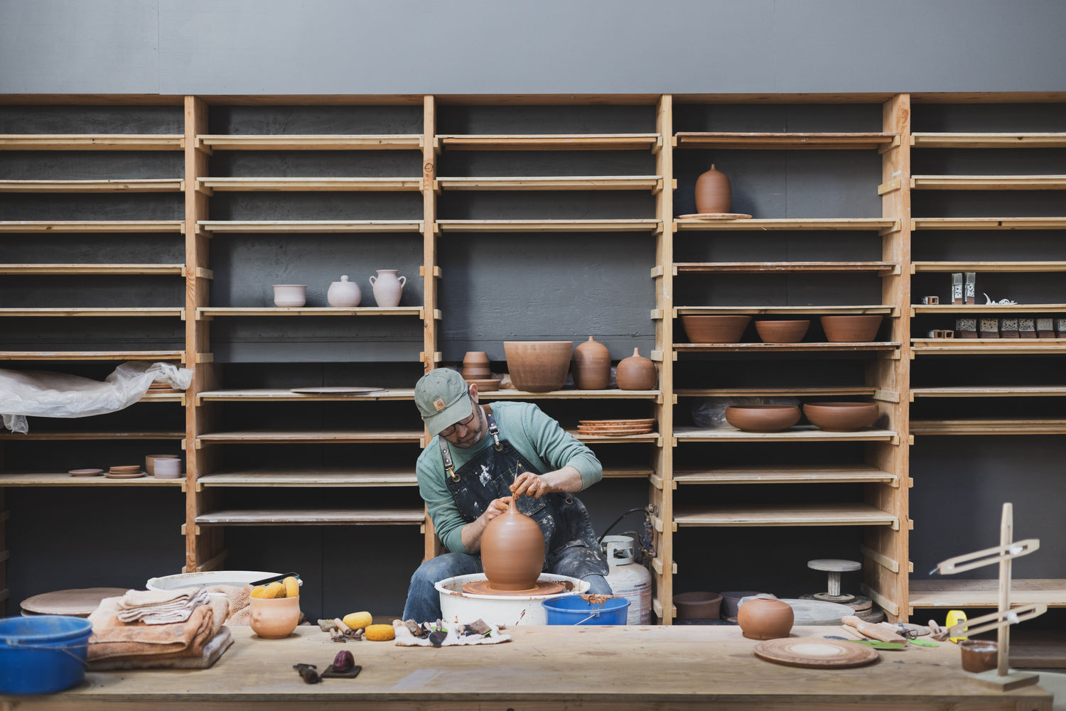 Josh sits at wheel and throws pottery at San Diego Ceramic Studio.