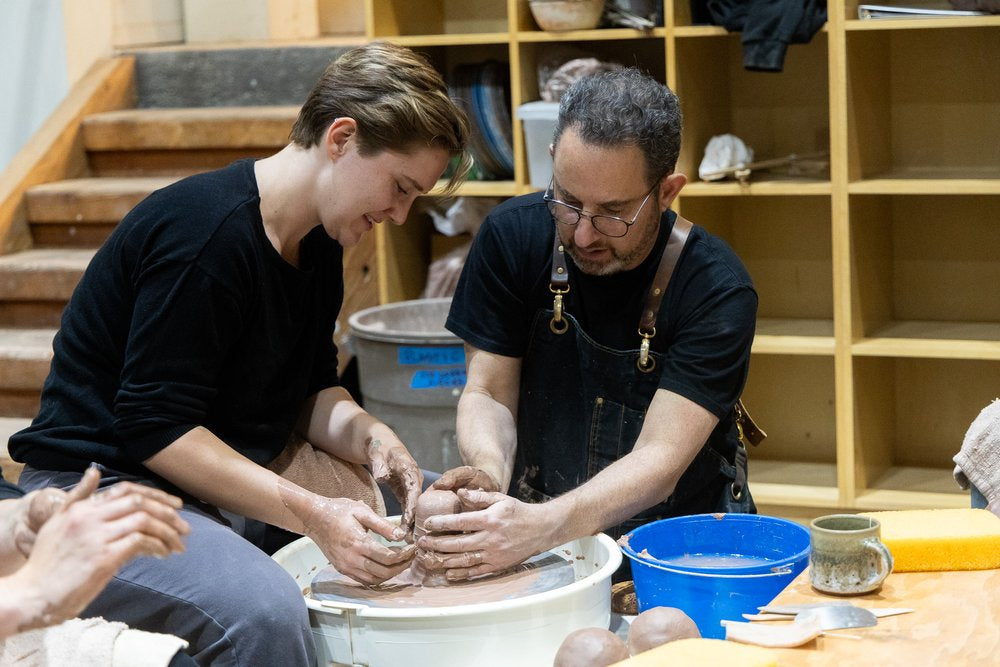 Beginner taking class at Tao of Clay. Teacher showing how to throw pottery.