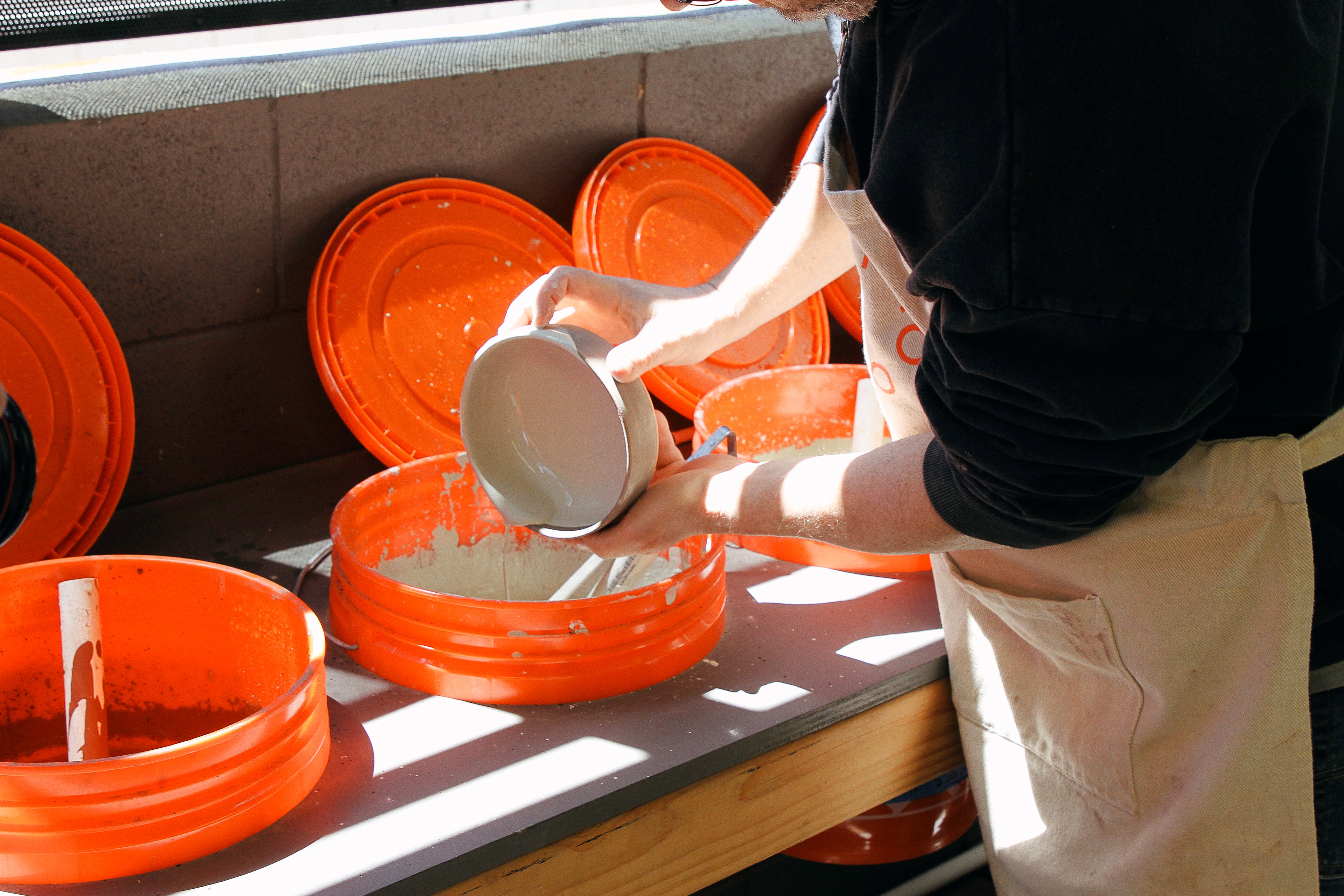 A student at Tao of Clay dipping a ceramic bowl in hand blended glaze at Tao of Clay.